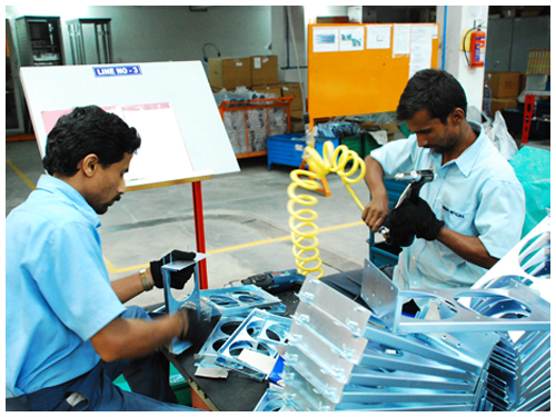 Two operators fitting formed sheet metal parts at a line workstation