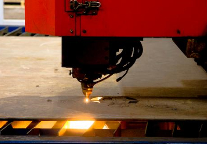 CNC laser cutting a steel sheet, molten edge glowing