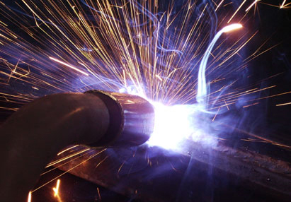 Close-up of a welding arc throwing sparks along a steel joint